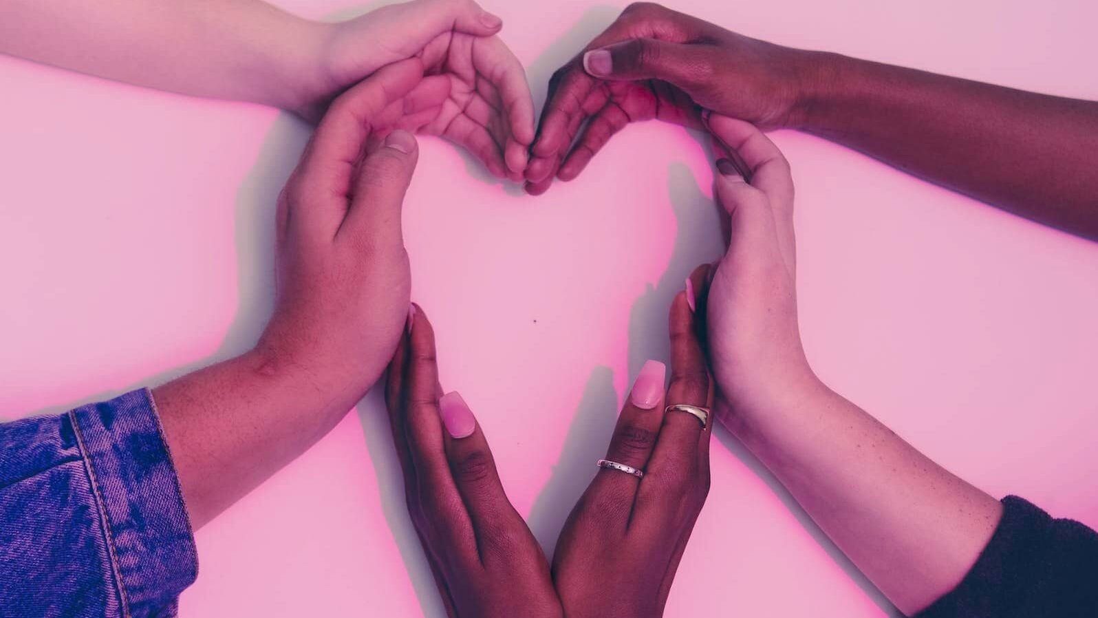 Human Hands Forming Heart on White Surface